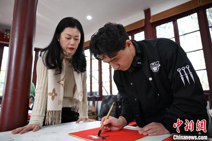 1月20日，外籍留學(xué)生在西泠印社社員李硯指導(dǎo)下寫福。當(dāng)日，來自巴西、馬來西亞、加納、哈薩克斯坦的外籍留學(xué)生在浙江杭州西泠印社體驗(yàn)福貼、春聯(lián)和篆刻，感受古老的中國傳統(tǒng)文化。中新社記者 王剛 攝