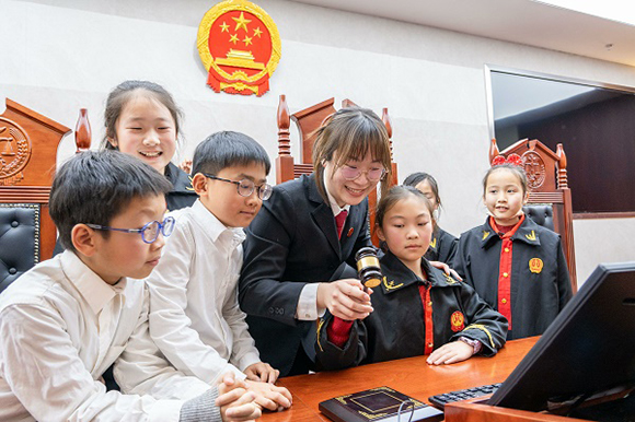 圖①：干警帶同學(xué)們體驗敲法槌。