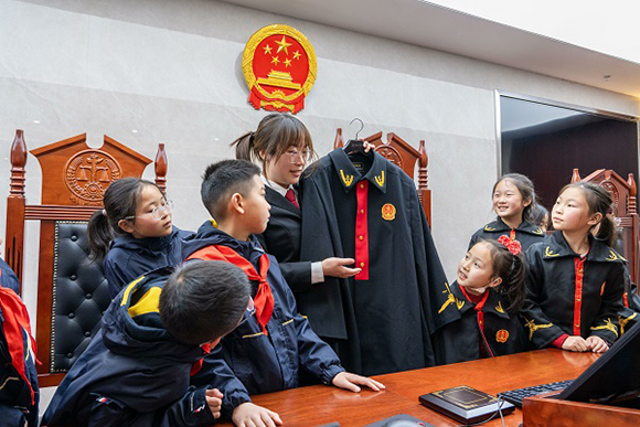 圖②：干警向同學(xué)們介紹法袍。