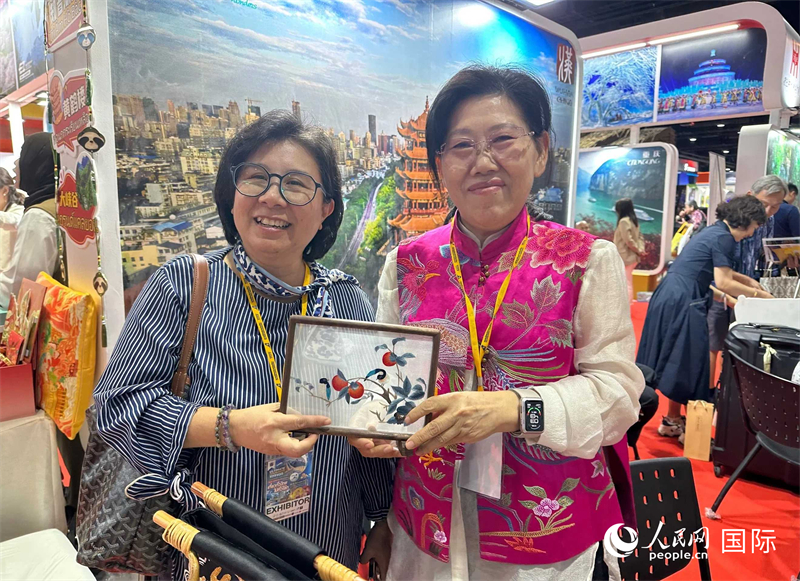 中國“大冶刺繡”傳承人劉小紅（右）參加泰國國際旅游展，向觀眾介紹中國非遺刺繡針法。人民網(wǎng)記者 簡承淵攝